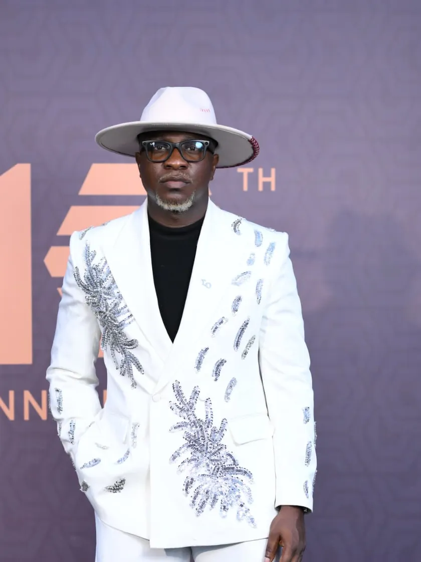 Theo Olayanju in an ivory embroidered suit and cream fedora