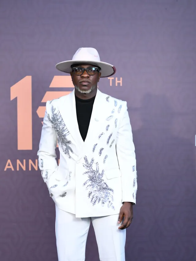 Theo in an ivory suit with silver botanical embroidery and a cream fedora