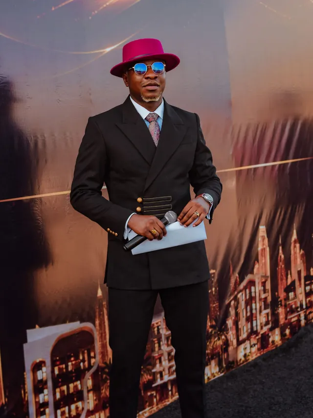 Theo hosting in black tailoring and a magenta fedora